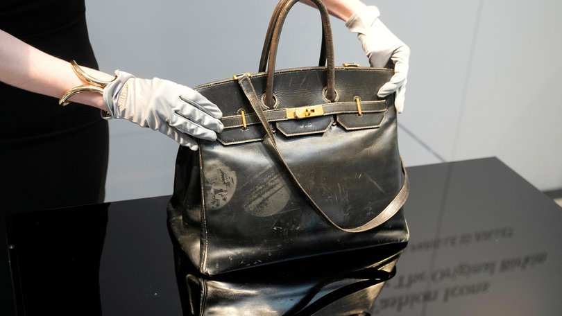 An auction officer displays the original Birkin bag created by Hermès for Jane Birkin in 1984, prior to its auction Thursday, July 10, 2025 in Paris. (AP Photo/Michel Euler) Michel Euler