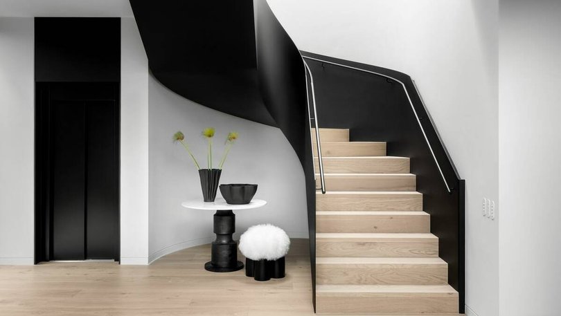 A black steel curved staircase leads to the main bedroom.