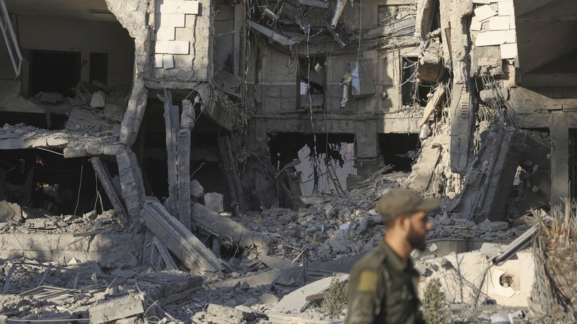A soldier passes in front the damaged Syrian Defence Ministry building which was hit by several Israeli airstrikes, in Damascus.
