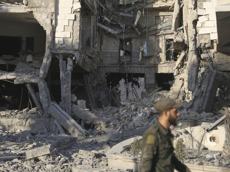 A soldier passes in front the damaged Syrian Defence Ministry building which was hit by several Israeli airstrikes, in Damascus.