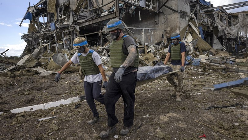 Ukrainian troops carry the body of a Russian soldier from a destroyed building at the Sudzha Border Crossing in Ukraine.