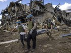 Ukrainian troops carry the body of a Russian soldier from a destroyed building at the Sudzha Border Crossing in Ukraine.