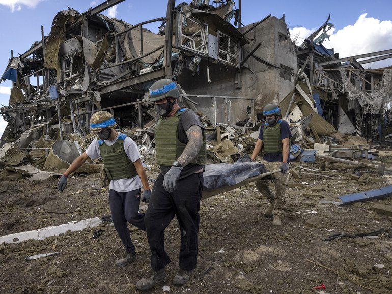 Ukrainian troops carry the body of a Russian soldier from a destroyed building at the Sudzha Border Crossing in Ukraine.