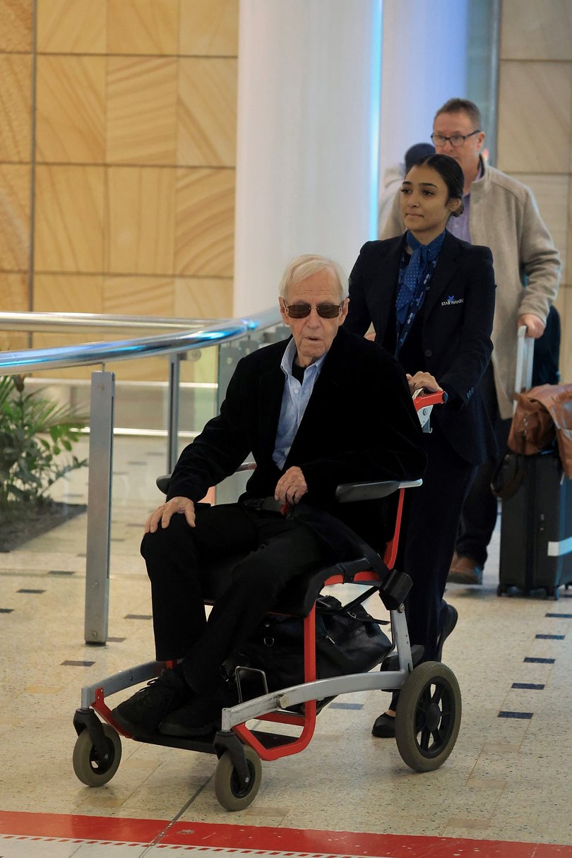 Paul Hogan, now 85, being wheeled in a ‘special assistance’ airport wheelchair by Qantas staff Picture: MEDIA-MODE