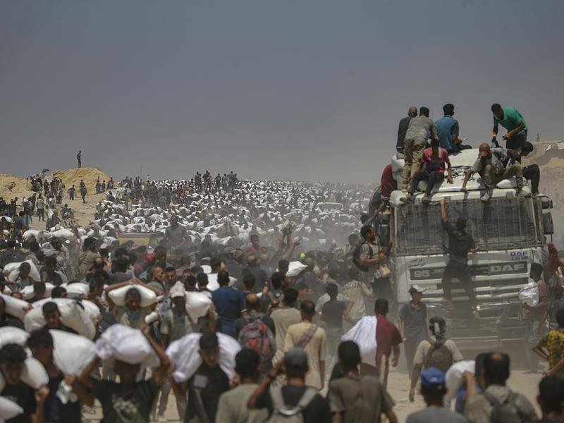 Gaza residents carry bags of flour after lorries with food aid were allowed into the enclave. (EPA PHOTO)