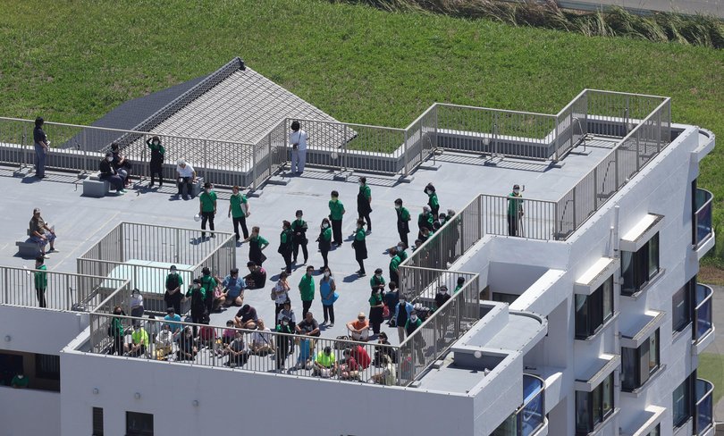 People gathered on the rooftops of buildings near the coast in Oamishirasato City, Chiba, Japan. 