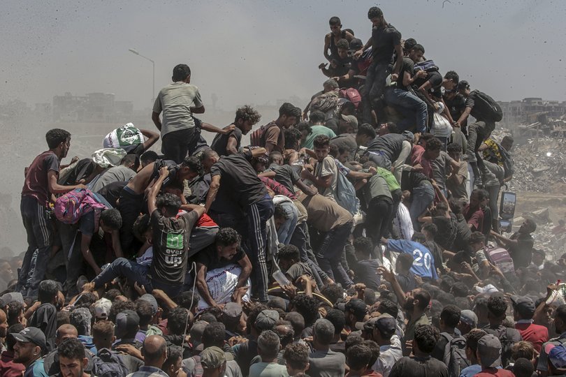 Internally displaced Palestinians try to grab bags of flour from an aid truck near a food distribution point in Zikim, northern Gaza Strip, 27 July 2025.