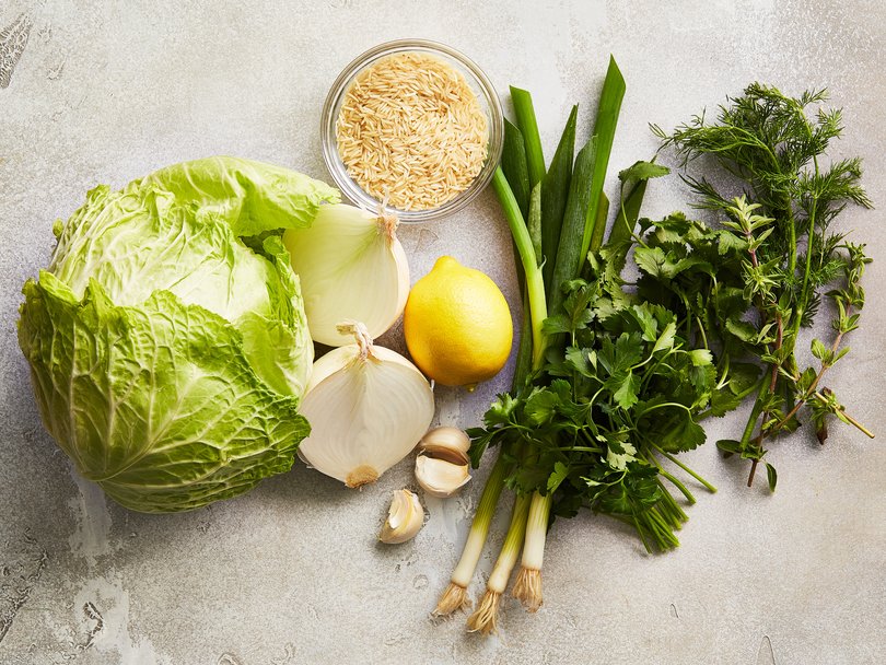Some of the ingredients for pork-cabbage casserole: savoy cabbage, onion, garlic, lemon, spring onions, long-grain rice and a blend of fresh herbs, in New York, February 1, 2023. Food stylist: Simon Andrews (Armando Rafael/The New York Times)