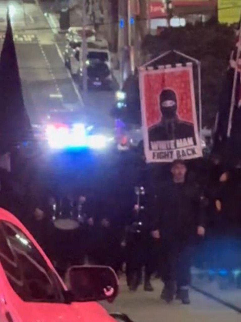 A large group of men dressed in black with their faces covered marched past Bourke Street Mall in Melbourne’s CBD at night. Some held a sign reading “White Man Fight Back.” Picture: TikTok
