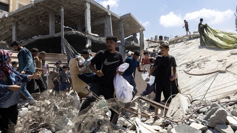 Palestinians rush to collect humanitarian aid that was dropped by parachute from planes flying over Gaza City on Thursday.