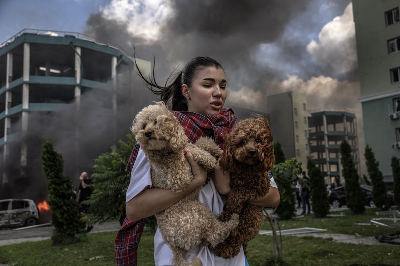 A Ukrainain woman carries pet dogs as she runs from her apartment block after Russian aerial bombs exploded in the area in Kharkiv.