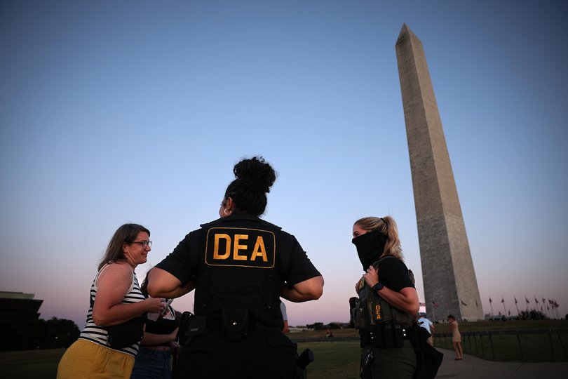 Drug Enforcement Administration (DEA) agents stop to talk with tourists as they patrol near the Washington Monument.
