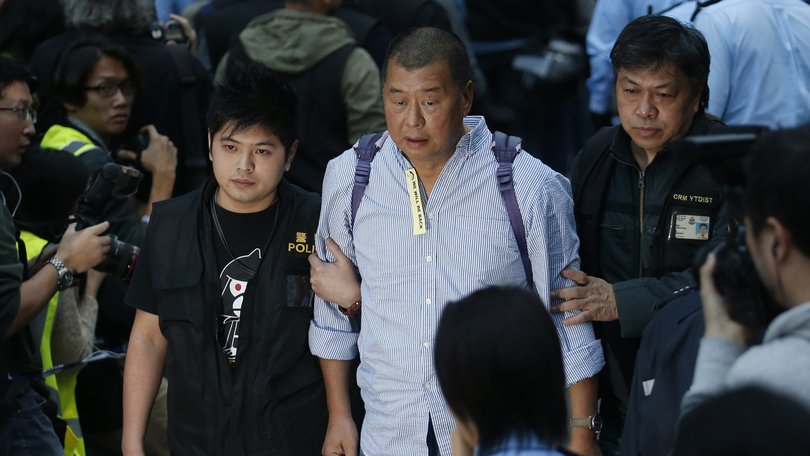 Hong Kong media magnate Jimmy Lai, centre, being taken away by police officers outside government headquarters in Hong Kong in 2014.