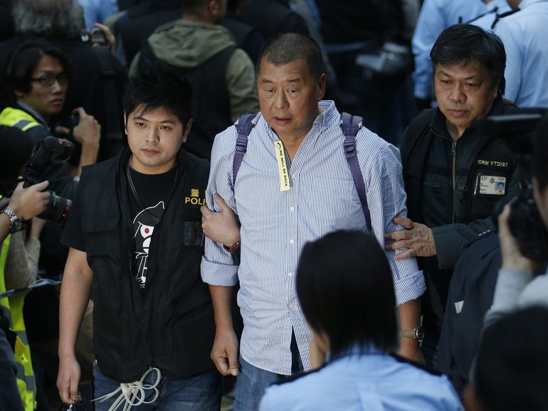 Hong Kong media magnate Jimmy Lai, centre, being taken away by police officers outside government headquarters in Hong Kong in 2014.