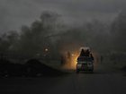 Palestinians ride their vehicles through black smoke along the Sea Road, at dusk in the south of Gaza City ion Thursday.