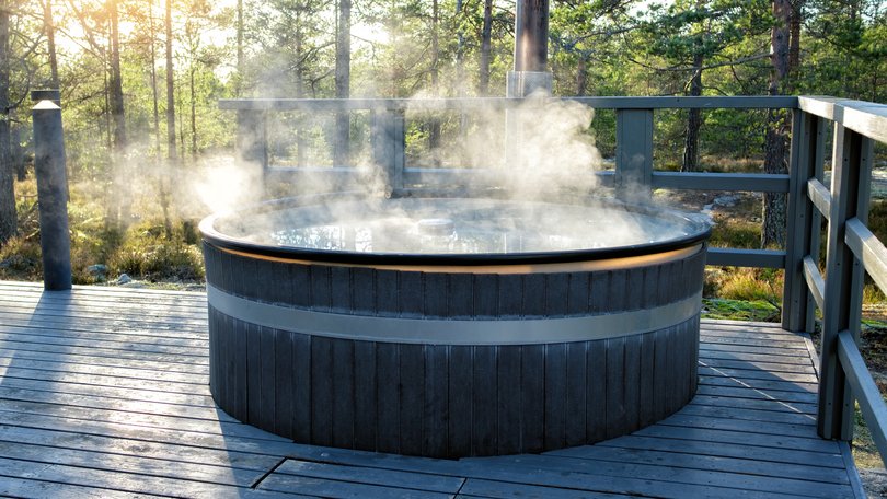 Modern big barrel outdoor hot tub in the middle of forest. The hot tub's soothing warm water relaxes muscles and eases tensions, so your worries can simply melt away.