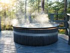 Modern big barrel outdoor hot tub in the middle of forest. The hot tub's soothing warm water relaxes muscles and eases tensions, so your worries can simply melt away.