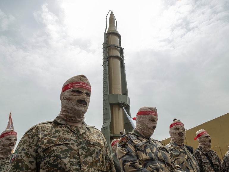 Islamic Revolutionary Guard Corps (IRGC) military personnel parade under an Iranian Kheibar Shekan Ballistic missile in downtown Tehran in 2022.