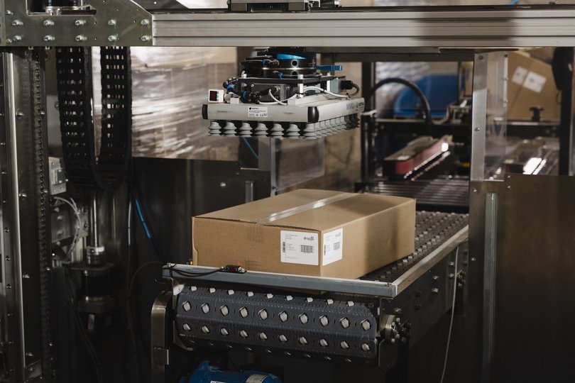 An industrial palletizer from Formic picks up a box at MattPak.