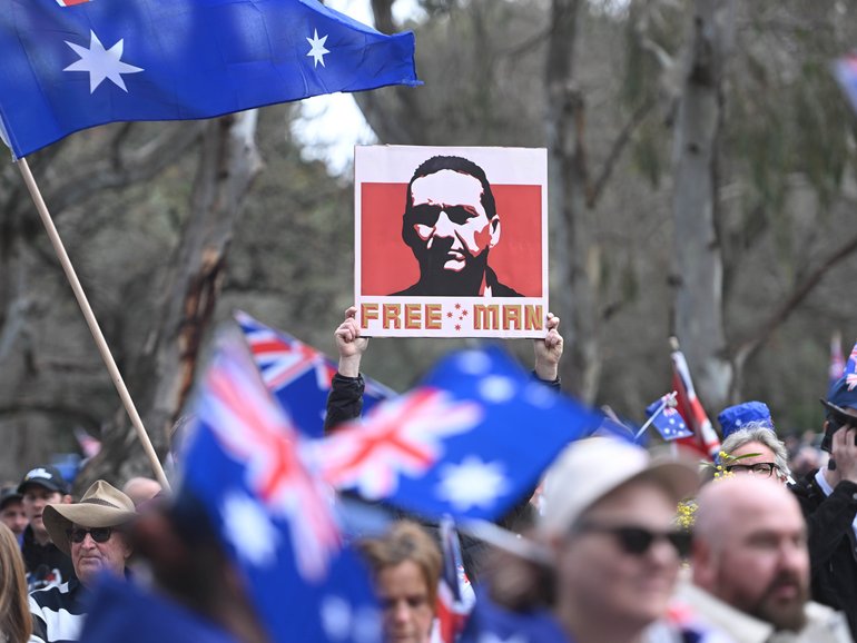 A man was seen holding a placard with an image of fugative Dezi Freeman at anti-immigration protesters march.
