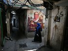 A woman walks past a wall poster depicting Abu Obaida, the spokesman for the Ezzedine al-Qassam Brigades, the armed wing of the Palestinian hamas movement, at the Burj al Barajneh camp for Palestinian refugees in Beirut's southern suburbs on May 20, 2025. 