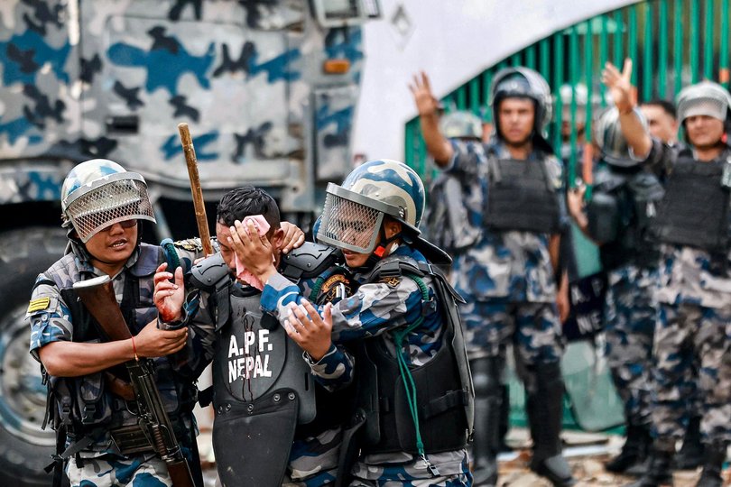 Riot police personnel carry an injured comrade as demonstrators pelt stones during a protest outside the Parliament in Kathmandu on September 8, 2025, condemning social media prohibitions and corruption by the government. At least 16 protesters were killed on September 8 after Nepal police fired rubber bullets, tear gas and water cannon to disperse demonstrators demanding the government lift its ban on social media and tackle corruption. (Photo by Prabin RANABHAT / AFP) Picture: PRABIN RANABHAT