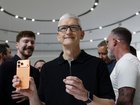 Apple CEO Tim Cook holds a next generation, as YouTuber Mr Beast looks on at Apple’s launch event. 