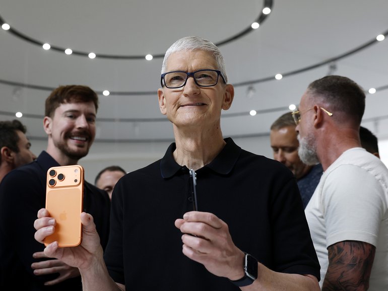 Apple CEO Tim Cook holds a next generation, as YouTuber Mr Beast looks on at Apple’s launch event. 