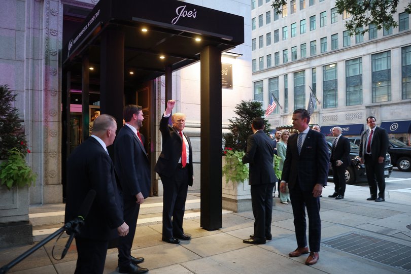 US President Donald Trump raises his fist into the air as he and members of his cabinet and administration arrive for dinner at Joe's Seafood.