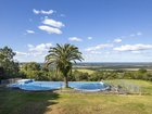 Green rolling hills, ocean views, and a fenced swimming pool.