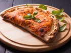 Pizza calzone with basil leaves close up 
