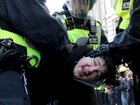 Police officers detain a protester during the Tommy Robinson-led Unite the Kingdom march.
