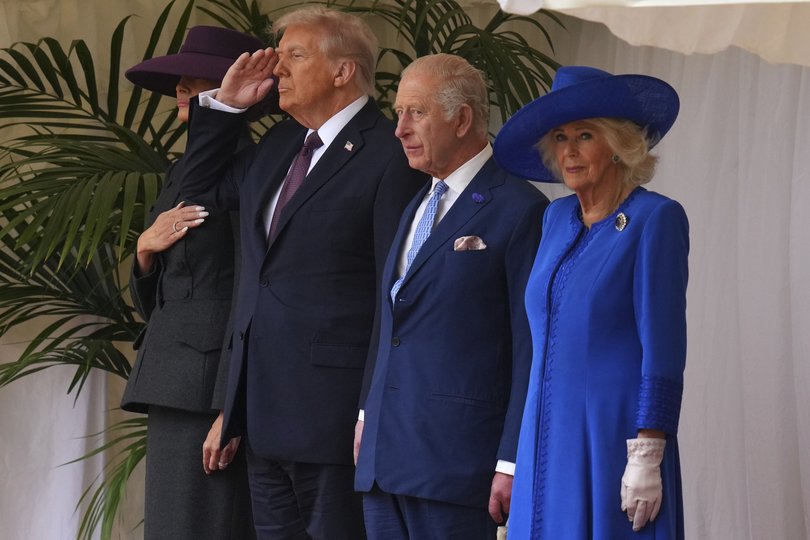 US President Donald Trump salutes as he stands beside King Charles III and Queen Camilla with Melania Trump during the national anthem at Windsor Castle.