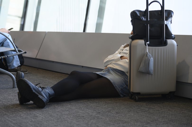 A passenger sits next to her luggage as she waits at the gate to board her flight.