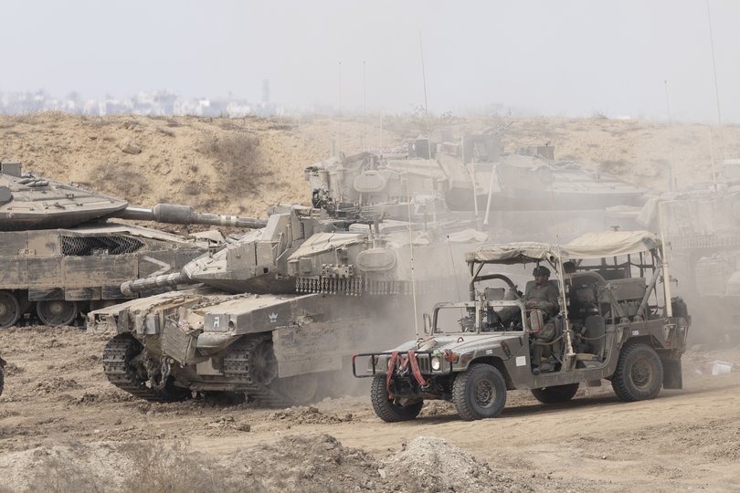 Israeli soldiers move with an army vehicle near Israeli tanks near the border with the Gaza Strip.