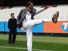 Snoop Dogg kicks a goal as Nick Daicos and Josh Daicos of the Magpies look on during an AFL Telstra Grand Final Entertainment Media Opportunity.