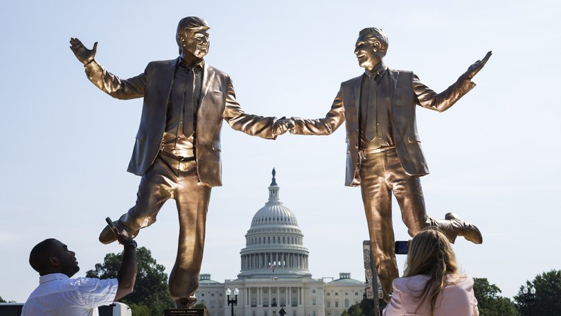 People stop to examine a statue featuring President Donald Trump and deceased financier Jeffrey Epstein outside the U.S. Capitol on Sept. 23. MUST CREDIT: Tom Brenner/For The Washington Post