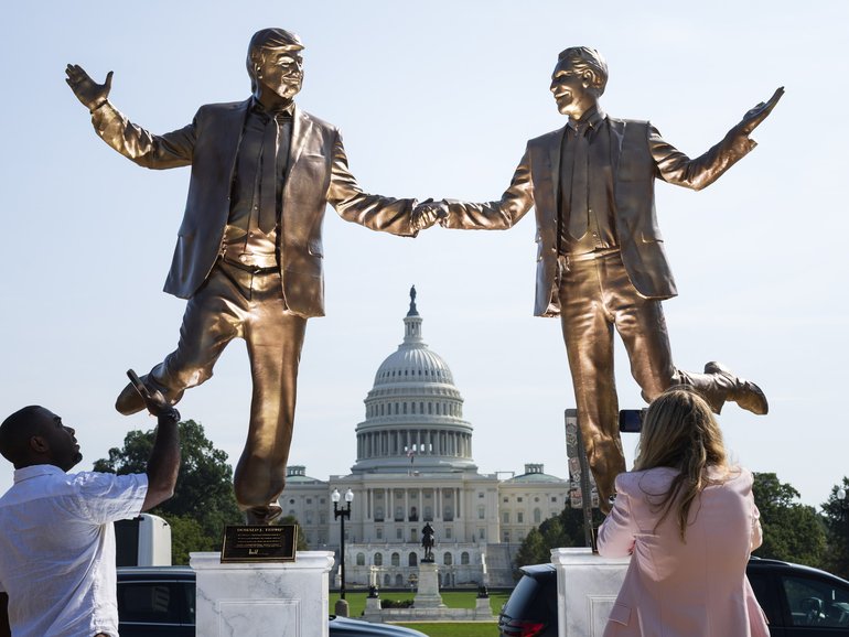 People stop to examine a statue featuring President Donald Trump and deceased financier Jeffrey Epstein outside the U.S. Capitol on Sept. 23. MUST CREDIT: Tom Brenner/For The Washington Post