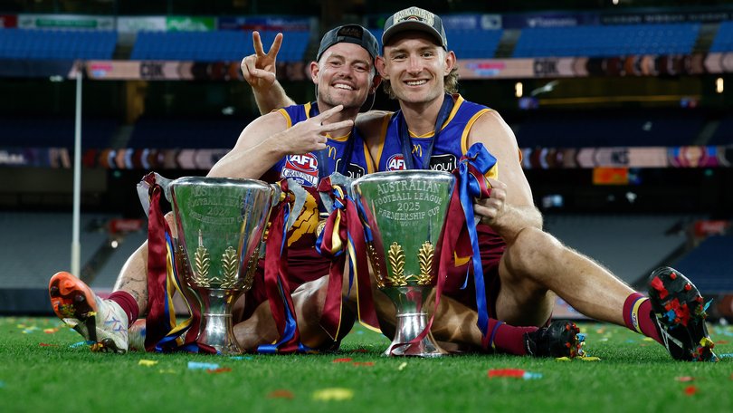 Lachie Neale (left) and Harris Andrews of the Lions (right) celebrate with the 2024 and 2025 Premiership Cups.