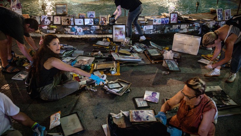 People clean and replace photos and items of victims of the October 7, 2023 Hamas attacks from the Dizengoff Square fountain memorial on October 05, 2025 in Tel Aviv, Israel. 