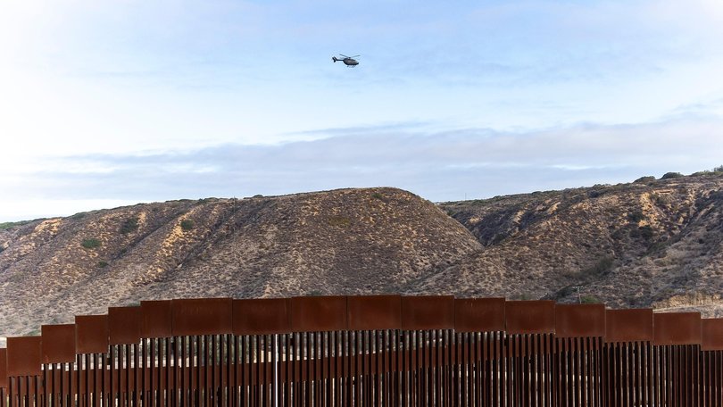 A helicopter monitors the border wall between Mexico and the US near Tijuana. 