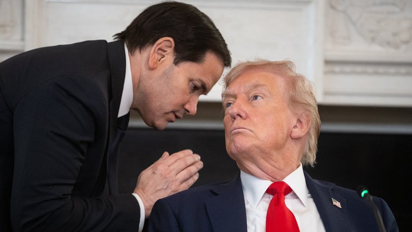 Secretary of State Marco Rubio whispers to US President Donald Trump as he hands him a note in the State Dining Room at the White House.