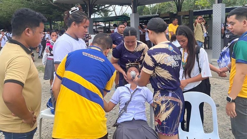 Students helping a fellow pupil as they gather outside the school buildings after an earthquake in Davao de Oro.