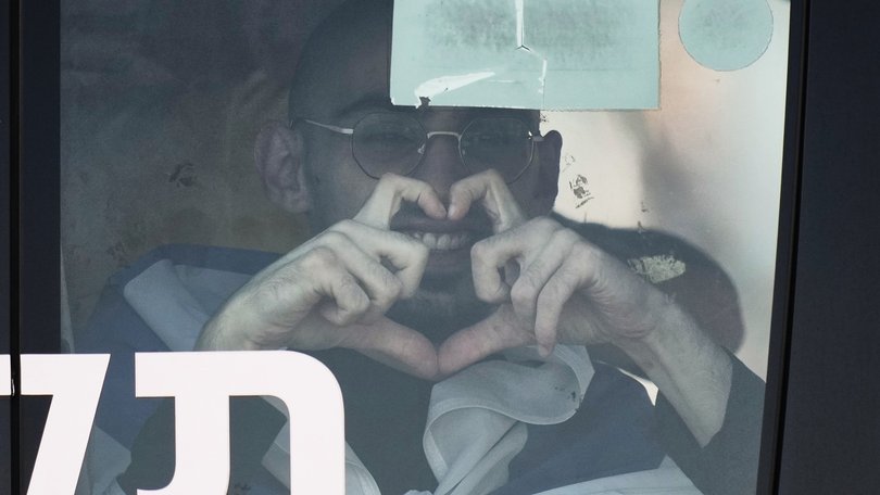 Rom Breslavski, an Israeli hostage released from the Gaza Strip smiles making a heart sign from a minibus at the Sheba Medical Center in Ramat Gan, Israel, Monday, Oct. 13, 2025. (AP Photo/Leo Correa)