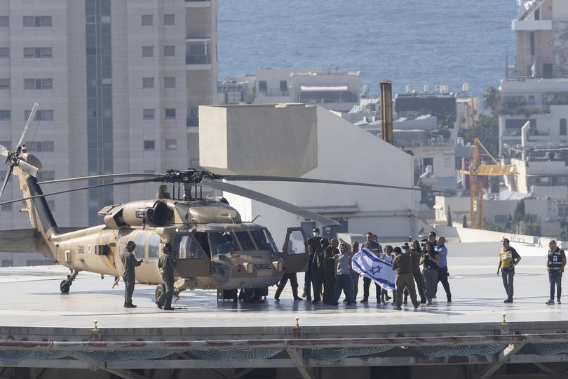 Released hostage Nimrod Cohen and his family wave to cheering crowd with Israeli flag, after landing at Ichilov Medical Centre following his release from Hamas captivity.