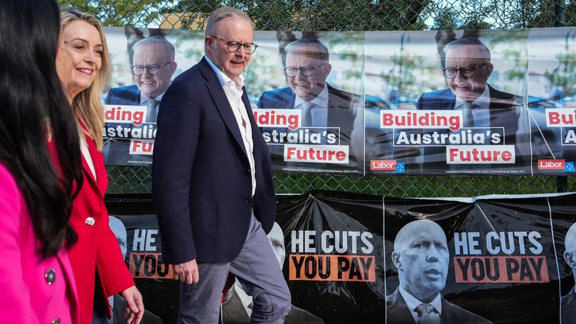 Prime Minister Anthony Albanese walks past election posters featuring himself and Opposition Leader Peter Dutton outside a polling station on May 03, 2025 in Sydney. 