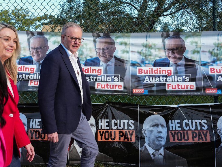 Prime Minister Anthony Albanese walks past election posters featuring himself and Opposition Leader Peter Dutton outside a polling station on May 03, 2025 in Sydney. 