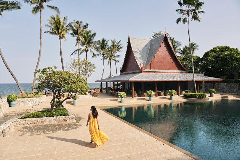 Traditional Thai architecture framed by lush greenery and palms surrounds the serene pool at Chiva-Som.