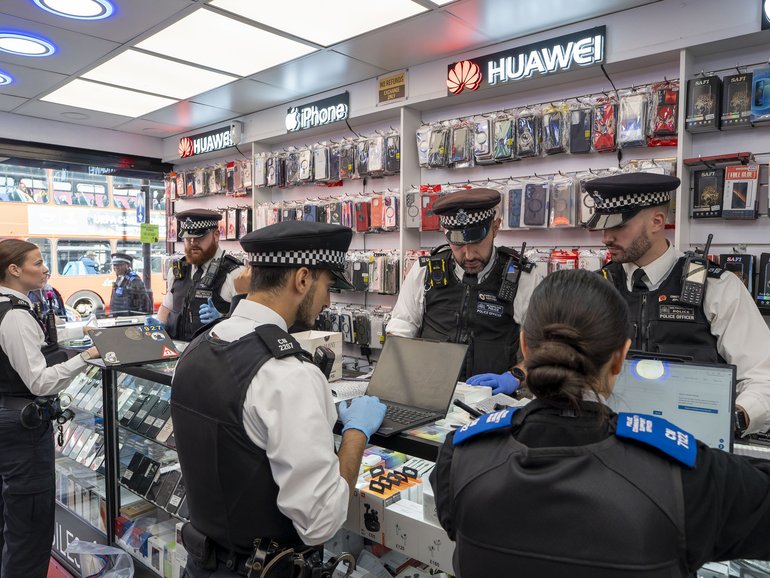 Police officers search a second-hand phone shop in London, September 25, 2025.