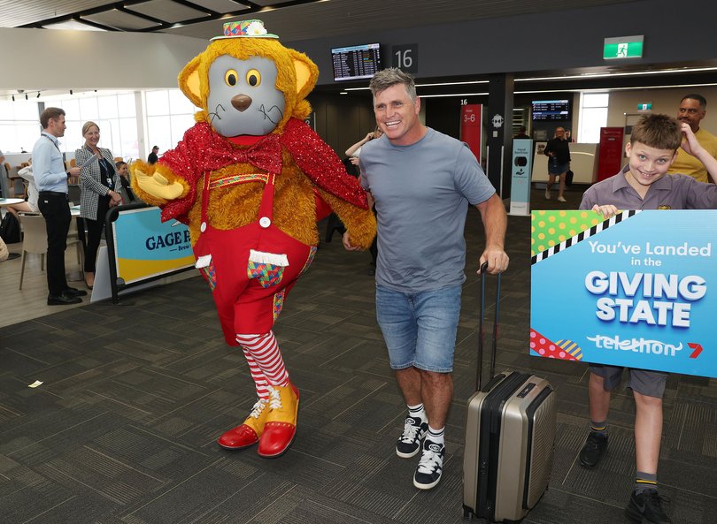 Shane Crawford is greeted by Fat Cat and St Francis Xavier Primary School student Henri Moore (11).